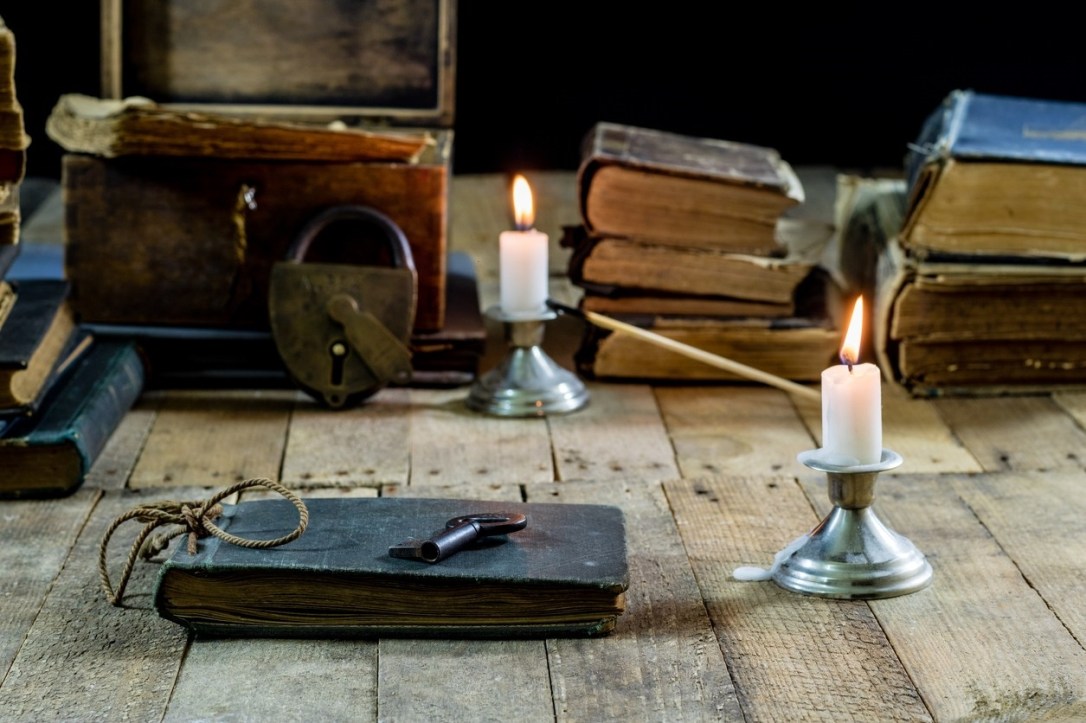 Old books and candles on a wooden table. Old room, reading room. Black background
